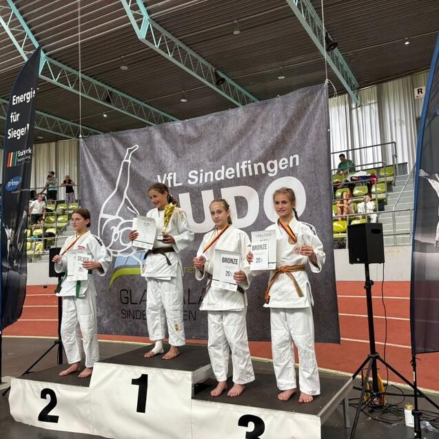 Siegerinnen auf dem Podium bei einem Judo-Wettkampf, halten ihre Urkunden in den H&auml;nden.