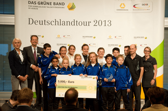 Gruppe von Kindern und Erwachsenen mit einem Scheck über 5.000 Euro, präsentiert bei der Deutschlandtour 2013.