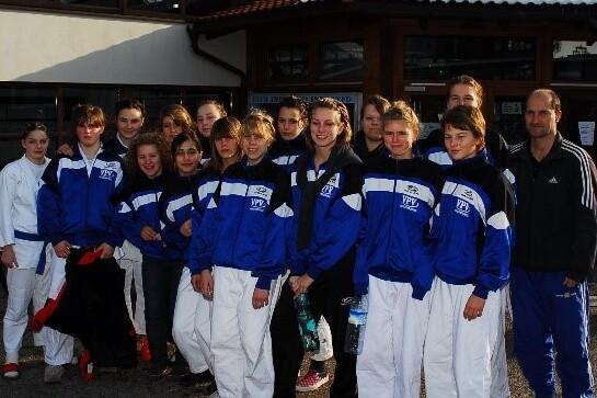 Gruppe junger Sportlerinnen in Trainingsanzügen vor einem Gebäude nach einem Wettkampf.