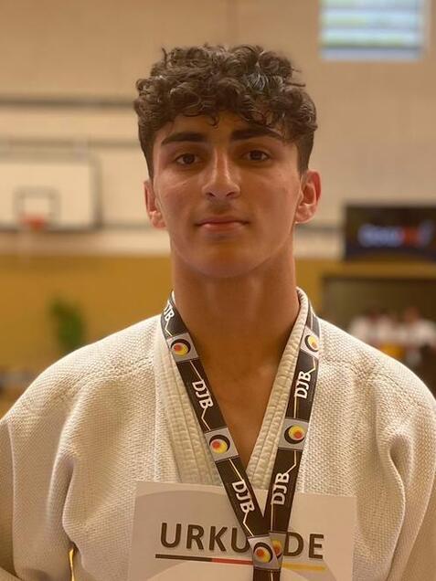 Junger Judo-Sportler in Wei&szlig; mit Medaille und Urkunde f&uuml;r den 2. Platz auf der Wettkampffl&auml;che.