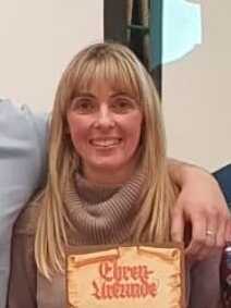 Gruppe von f&uuml;nf Personen h&auml;lt Urkunden und l&auml;chelt vor einem Projektorbildschirm mit der Aufschrift &bdquo;Ehrung f&uuml;r das Vereinsmitglieder&ldquo;.