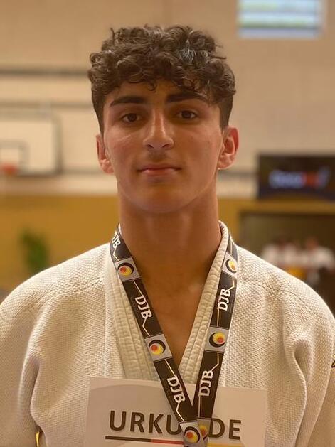 Junger Judo-Sportler in Wei&szlig; mit Medaille und Urkunde f&uuml;r den 2. Platz auf der Wettkampffl&auml;che.