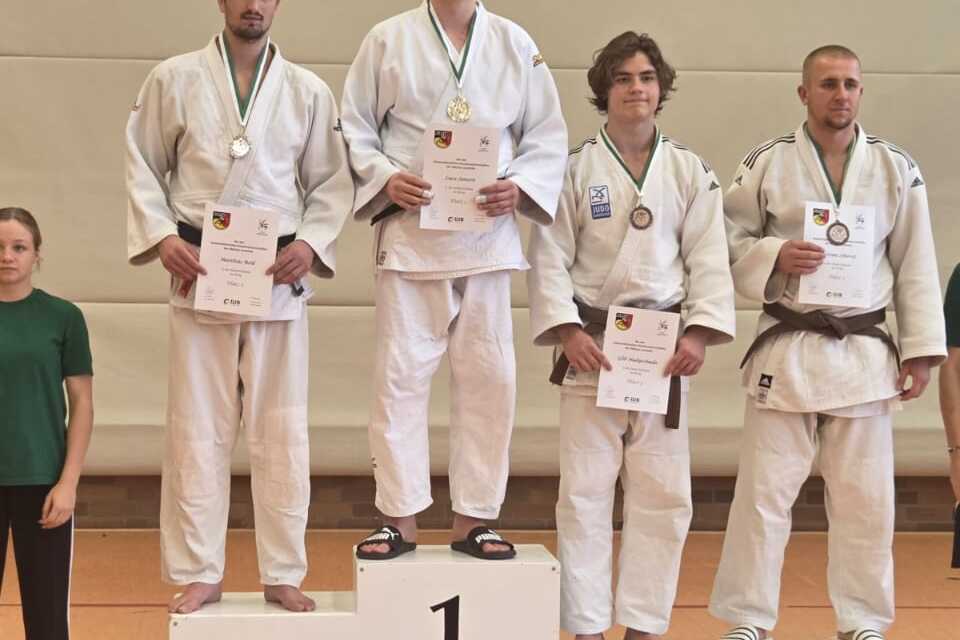 Sieben Personen stehen auf dem Siegerpodest einer Sportveranstaltung, drei in Judoanz&uuml;gen mit Medaillen.