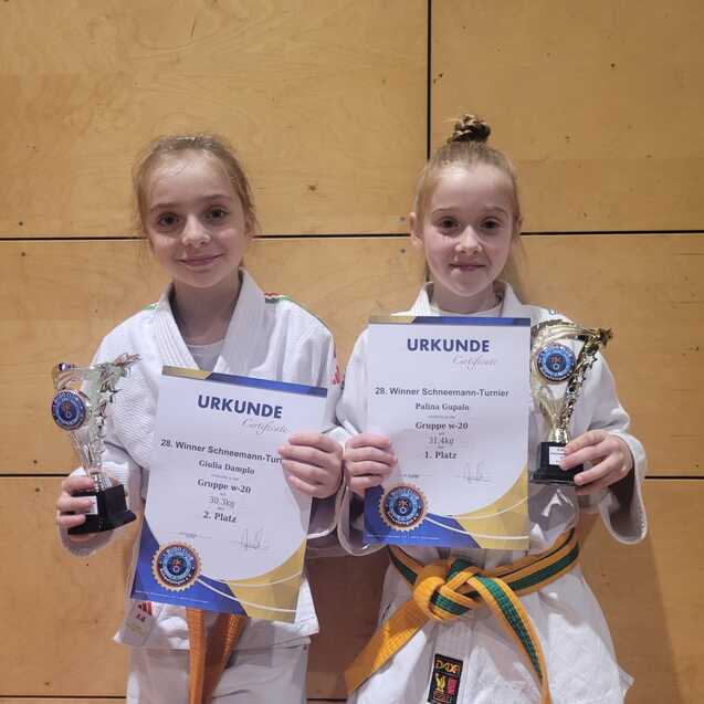 Zwei Kinder in Karateanz&uuml;gen halten Pokale und Urkunden f&uuml;r den zweiten Platz bei einem Wettkampf.