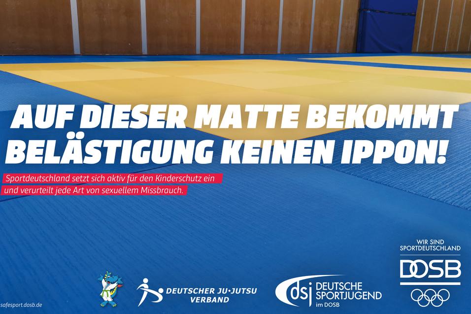 Blau-gelbe Kampfsportmatte in Turnhalle; Schrift: „Auf dieser Matte bekommt Belästigung keinen Ippon!“
